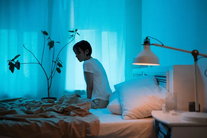 A woman sitting up in bed at night, wide awake